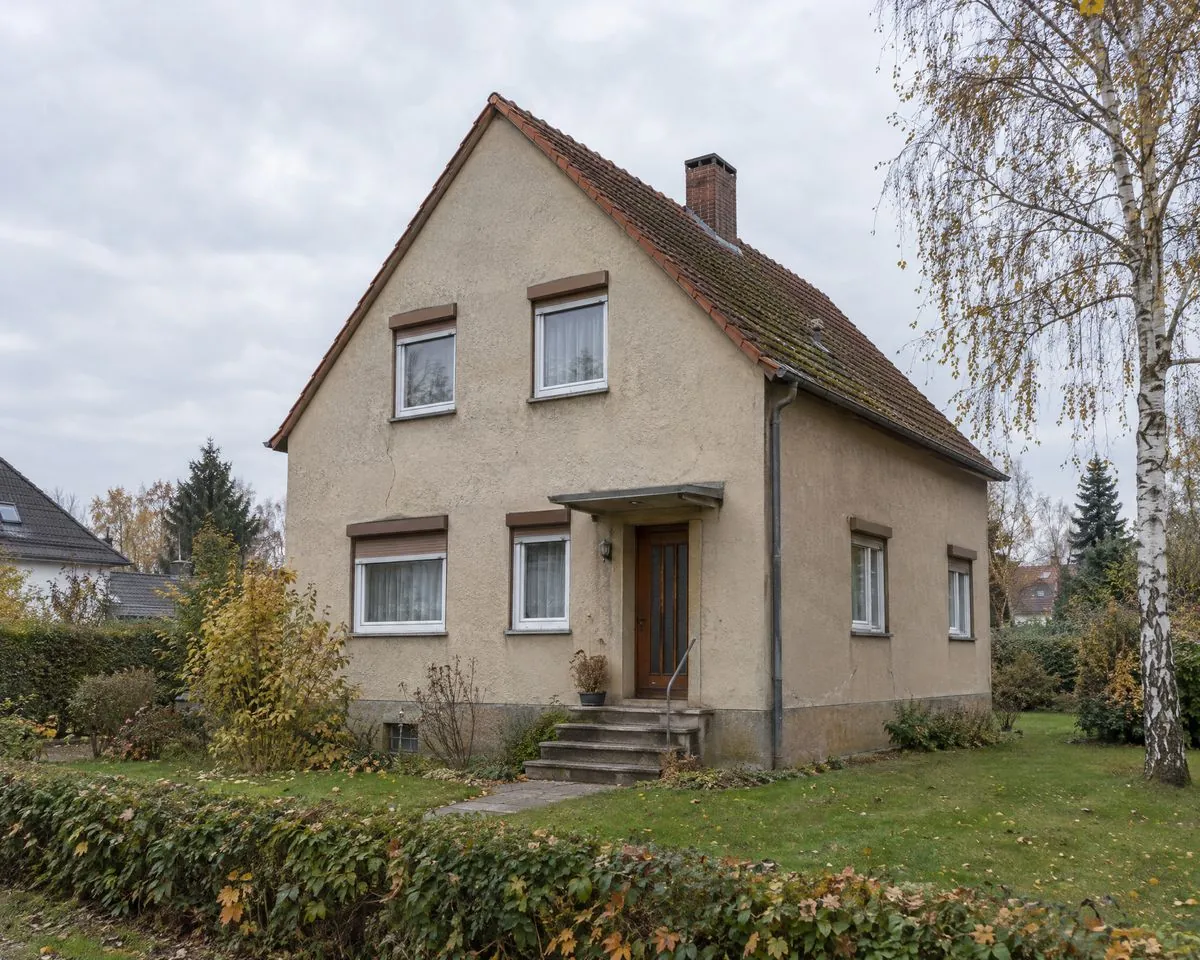 Typisches Einfamilienhaus aus den 1960er-Jahren vor der Sanierung: alter Putz, alte Fenster, altes Dach mit Schornstein
